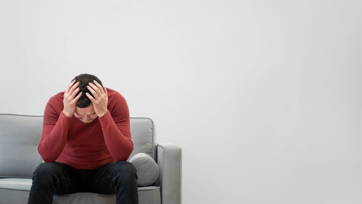 Veteran sitting on a couch with his head in his hands, showing signs of PTSD